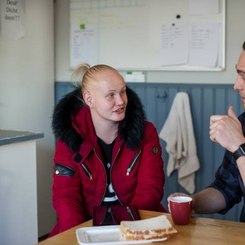 Vrouw en man praten zittend aan de keukentafel met lunch