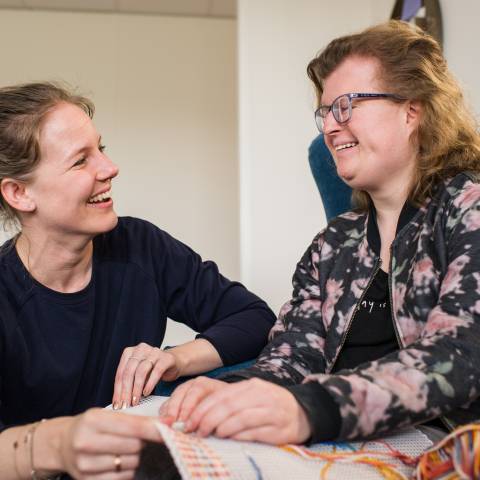 Vrouwen lachen bij borduurwerk