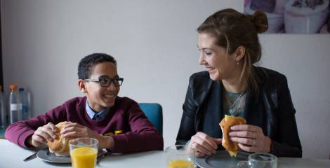 Jongen en begeleidster lunchen aan tafel