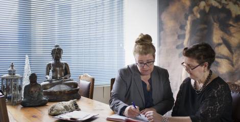 Twee vrouwen in gesprek aan een bureau met buddhabeelden